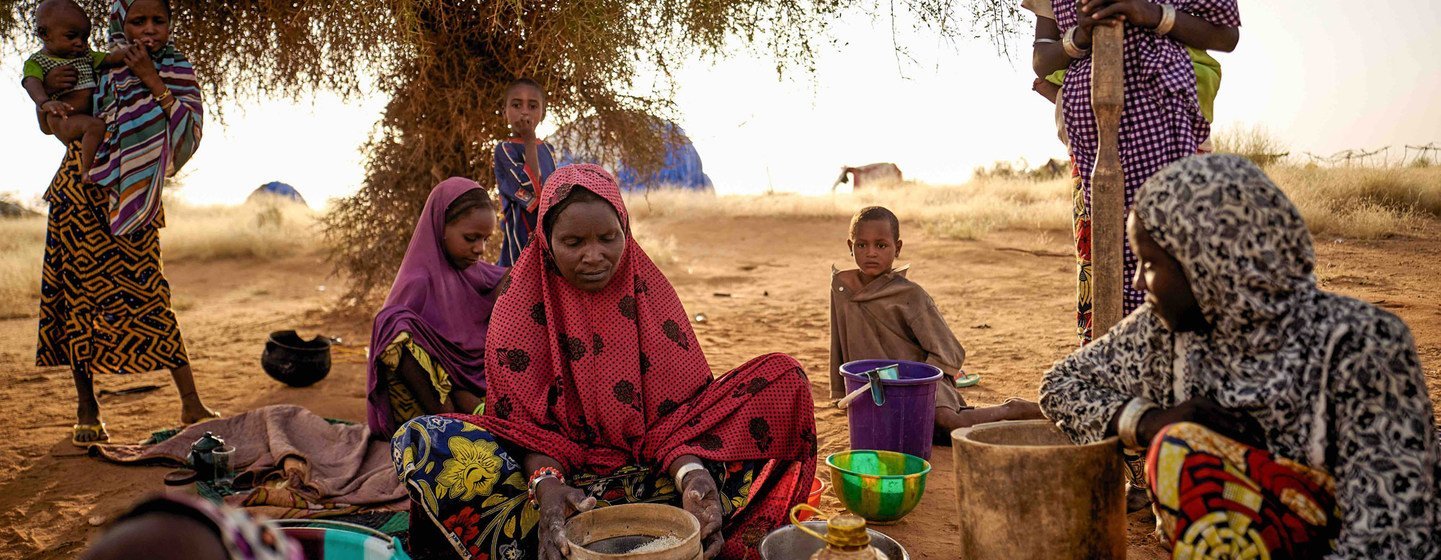 Sahel : des femmes déplacées par le changement climatique préparent de la nourriture dans un camp informel à Bagoundié, au Mali.