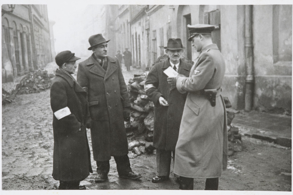 Bir Alman polis memuru, Krakow gettosundaki Yahudilerin kimlik belgelerini kontrol ediyor.  Polonya.  1941 dolaylarında.