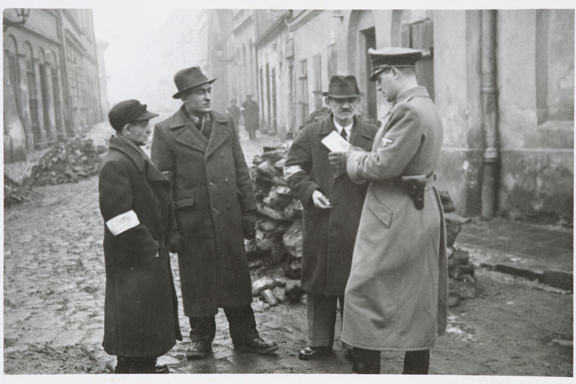 شرطي ألماني يتحقق من أوراق هوية اليهود في حي كراكوف في بولندا. حوالي عام 1941.