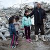 Uma família da área de Rumaila, no distrito de Jableh, no noroeste da Síria, próxima a sua casa destruída