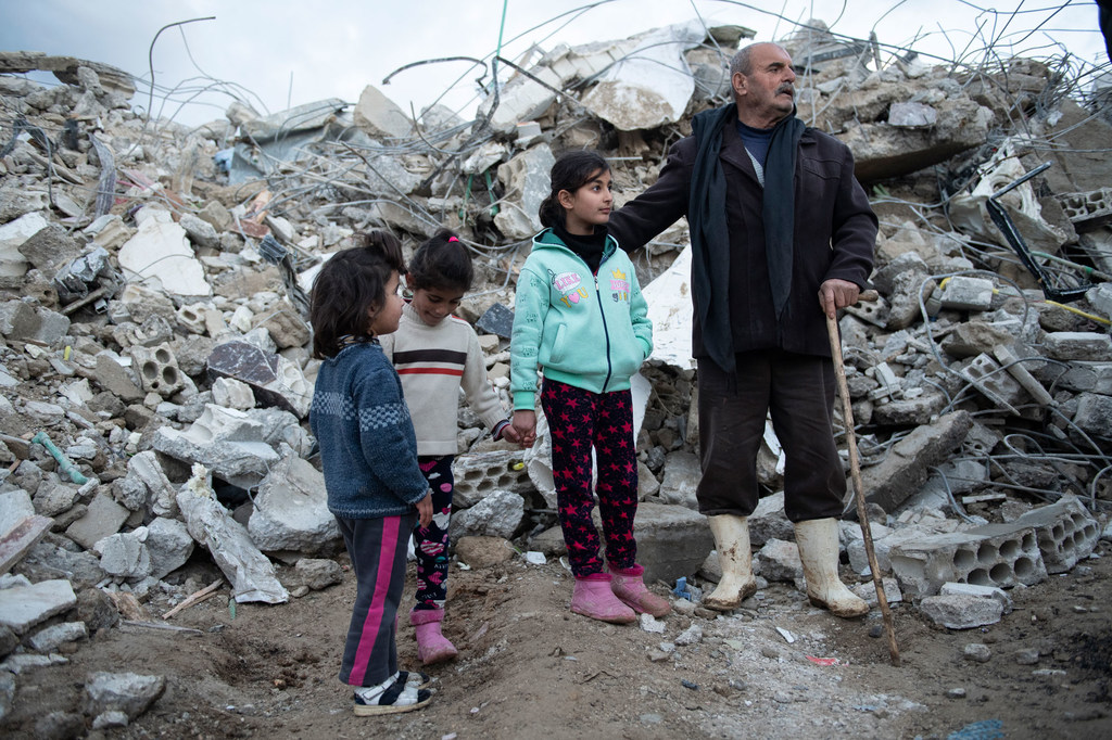 在叙利亚西北部，一个家庭站在他们被摧毁的房子废墟前。