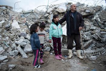 A family from the Rumaila area in Jableh district, in northwestern Syria stands close to their destroyed house.