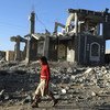 فتاة تسير أمام أنقاض مبانٍ مدمرة بسبب الحرب في صنعاء باليمن.