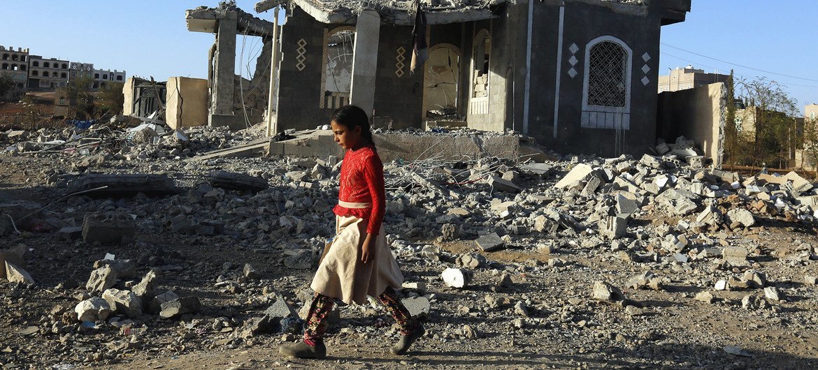فتاة تسير أمام أنقاض مبانٍ مدمرة بسبب الحرب في صنعاء باليمن.