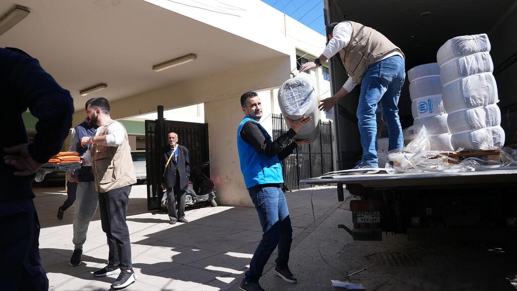 联合国工作人员在黎巴嫩南部西顿的一个避难所向流离失所家庭分发援助物品。