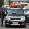 Une camionnette Hyundai noire chargée de bagages sur son toit est arrêtée dans la circulation au point frontalier de Masnaa au Liban. Plusieurs hommes se tiennent à proximité alors qu'ils attendent de traverser la Syrie pour échapper aux bombardements israéliens.