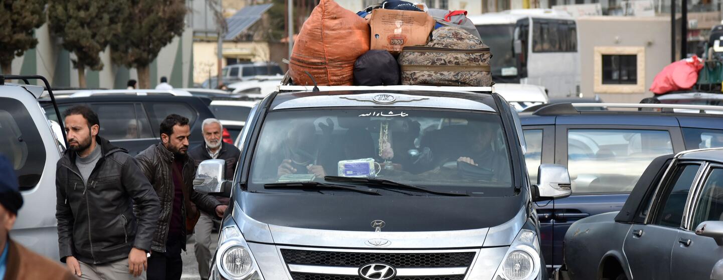 Une camionnette Hyundai noire chargée de bagages sur son toit est arrêtée dans la circulation au point frontalier de Masnaa au Liban. Plusieurs hommes se tiennent à proximité alors qu'ils attendent de traverser la Syrie pour échapper aux bombardements israéliens.