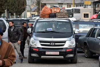 Une camionnette Hyundai noire chargée de bagages sur son toit est arrêtée dans la circulation au point frontalier de Masnaa au Liban. Plusieurs hommes se tiennent à proximité alors qu'ils attendent de traverser la Syrie pour échapper aux bombardements israéliens.