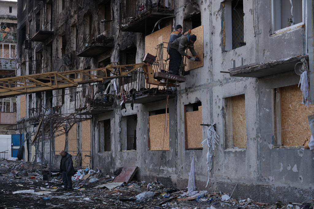 Workers secure plywood boards over the shattered windows of a residential building damaged by a missile strike in eastern Ukraine. (file)