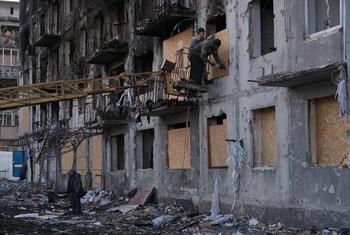 Workers secure plywood boards over the shattered windows of a residential building severely damaged by a missile strike on 7 March in Dobropillia in eastern Ukraine. (file)