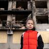 Восьмилетняя девочка стоит перед разрушенным бомбардировкой жилым домом в Доброполье, Украина.