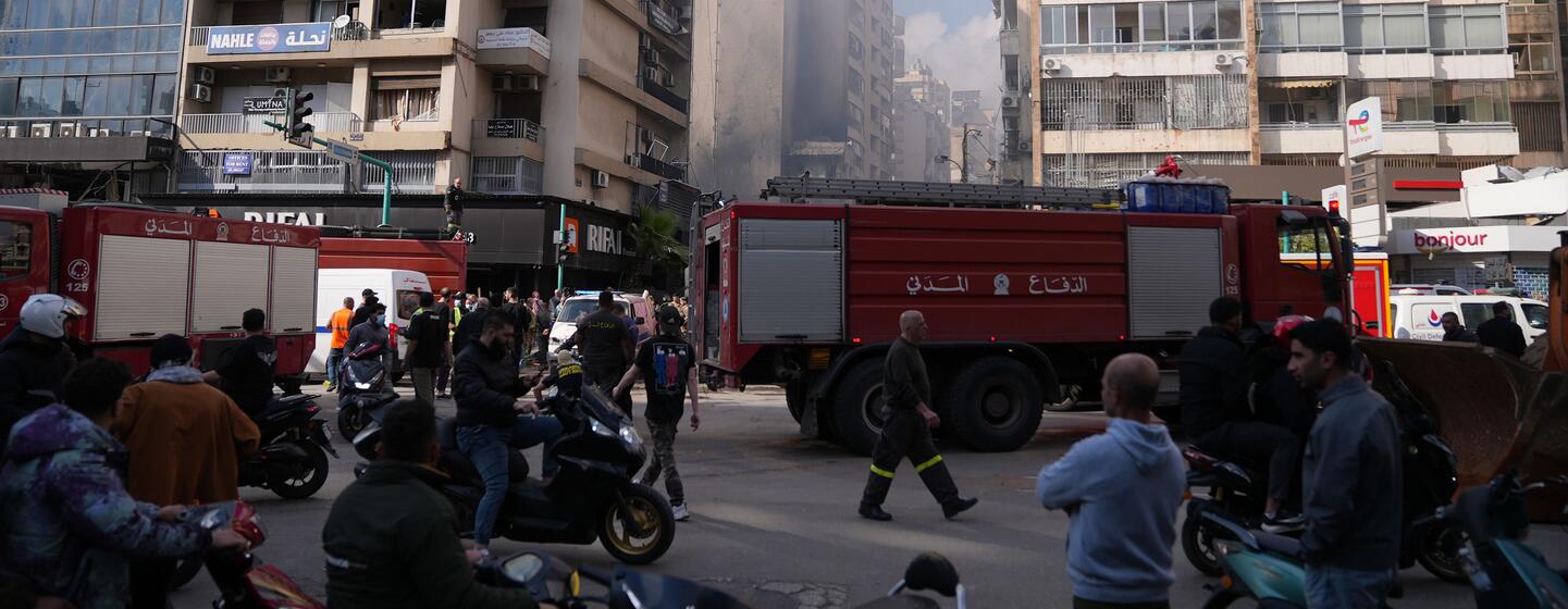 Des véhicules de secours et des civils se rassemblent dans une rue de Beyrouth au milieu de la fumée et de bâtiments endommagés à la suite de frappes aériennes.
