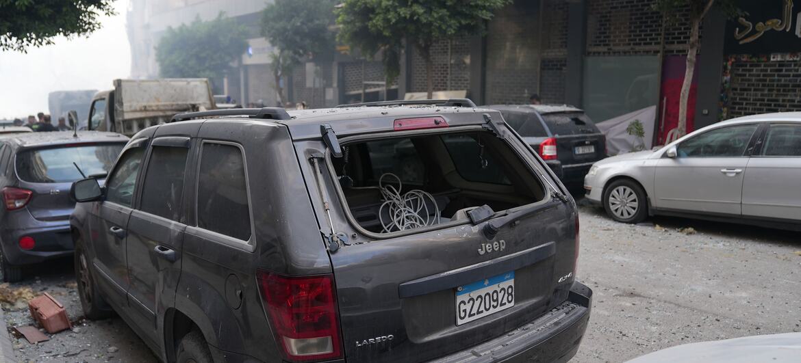 Un SUV Jeep gris endommagé, avec sa vitre arrière brisée et des débris éparpillés dans la rue à Beyrouth, au Liban, à la suite de frappes aériennes.