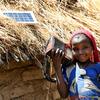 चाड के एक गाँव में, एक लड़की सौर ऊर्जा से संचालित रेडियो सुनते हुए.