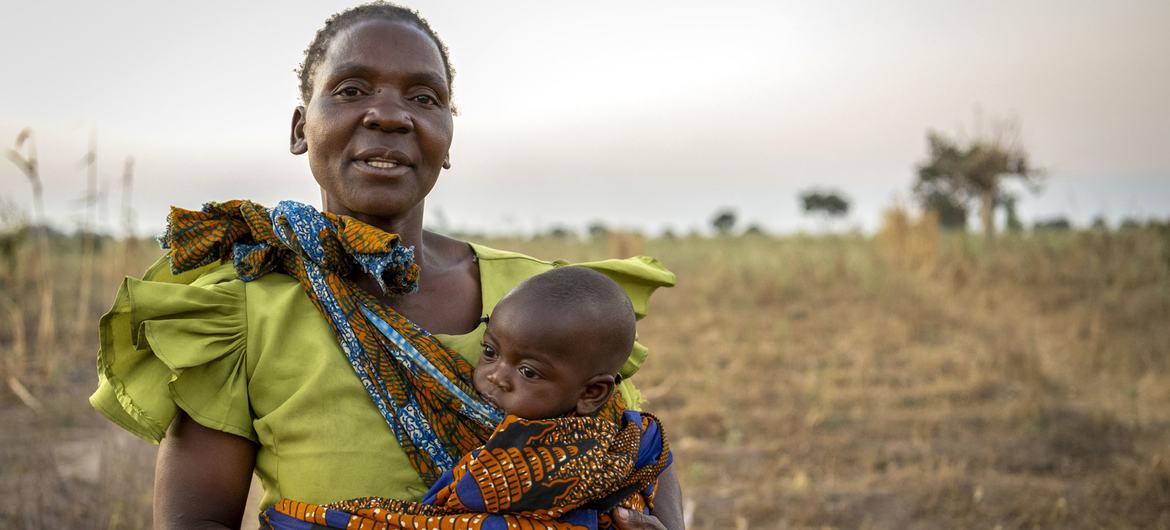 A mother stands on her drought-stricken land in Malawi.