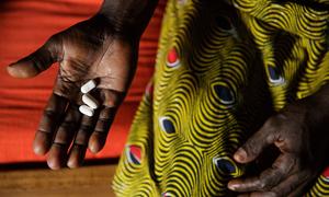 In Côte d'Ivoire, a woman living with HIV holds three pills she takes daily as part of antiretroviral therapy.