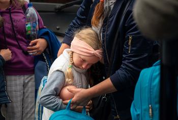 A 5-year-old girl named Yana is comforted by her mother Yevheniia at a transit point in Zaporizhzhia, Ukraine, while waiting to board a bus for Poland.