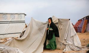 A woman stands by a tent in Gaza.