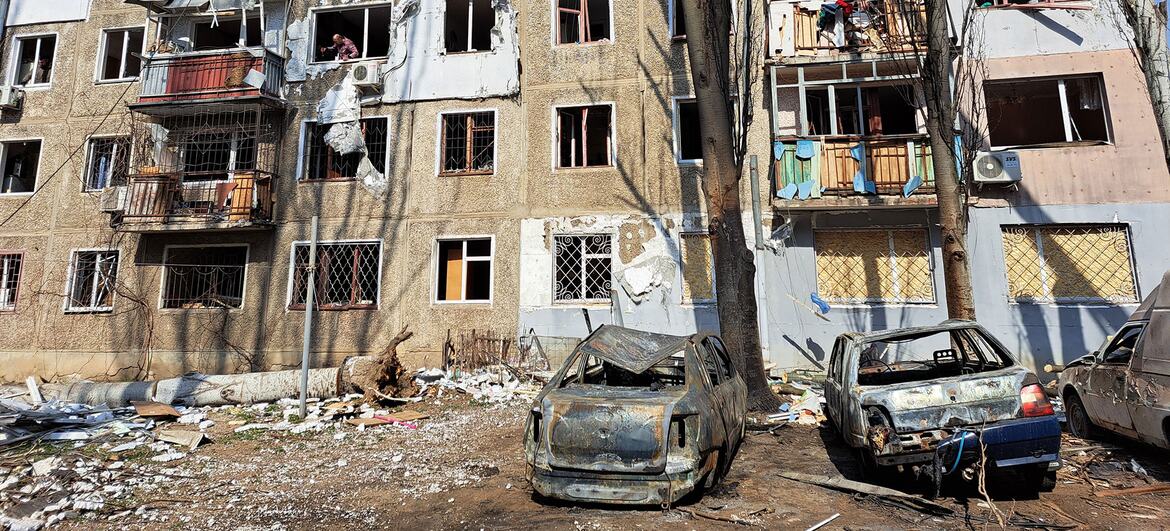 Immeuble d'appartements endommagé avec des voitures incendiées devant à Mykolaïv, en Ukraine.