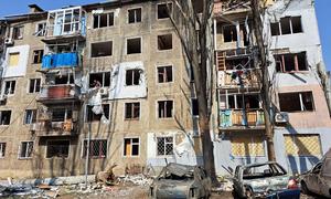 Immeuble d'appartements endommagé avec des voitures incendiées devant à Mykolaïv, en Ukraine.