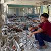 Criança sentada entre as ruínas de uma escola no centro de Gaza