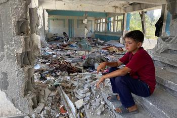Criança sentada entre as ruínas de uma escola no centro de Gaza