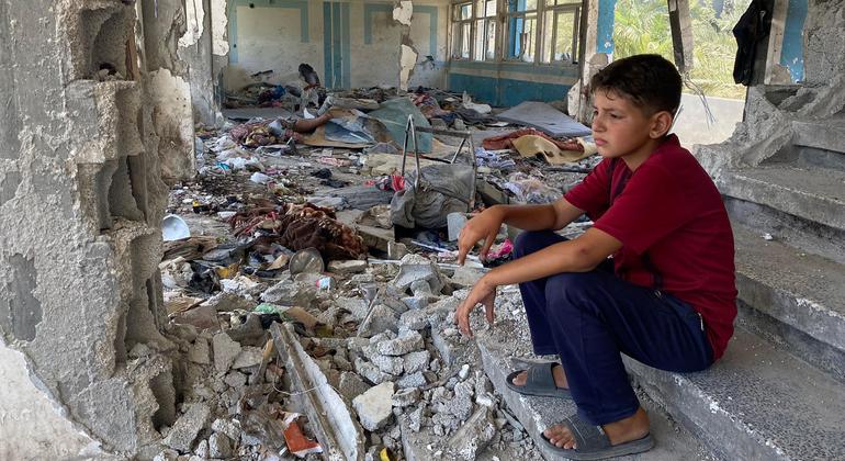 一个孩子坐在加沙中部一所学校的废墟中。