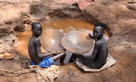 Wavulana wawili wadogo wakitafuta dhahabu kwenye shimo lenye matope.