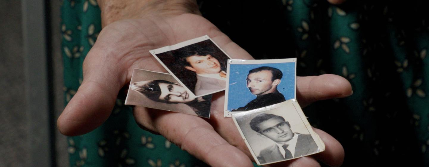 Kada Hotić holds photographs of her son, husband, and two brothers, who were lost in the Srebrenica genocide.