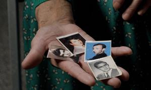 A woman holds the photos of who her husband and two brothers who were murdered in the 1995 Srebrenica genocide.
