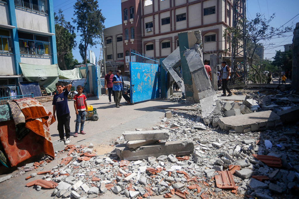 مواطنون يفحصون حجم الدمار بعد قصف مدرسة وسط قطاع غزة.