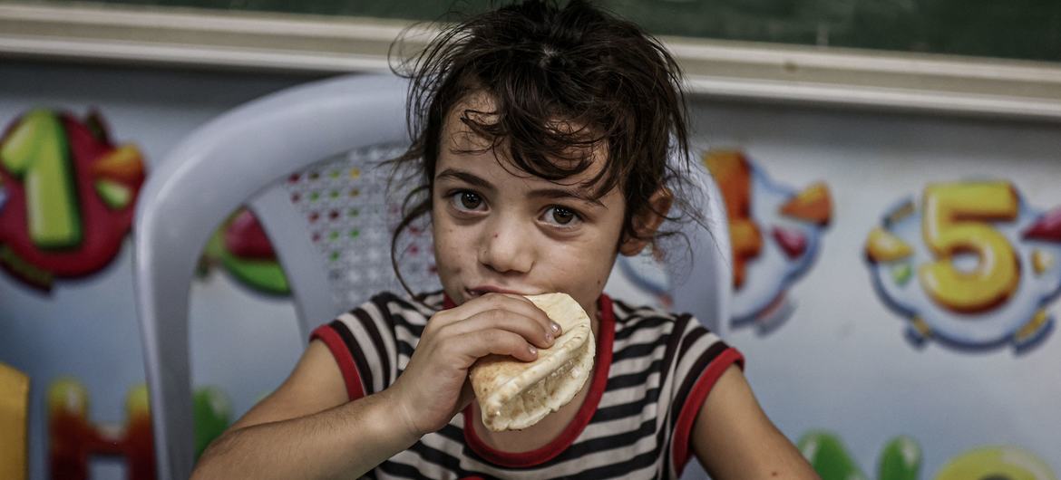 A young girl eats bread distributed by the World Food Programme at an UNRWA school in Gaza. 