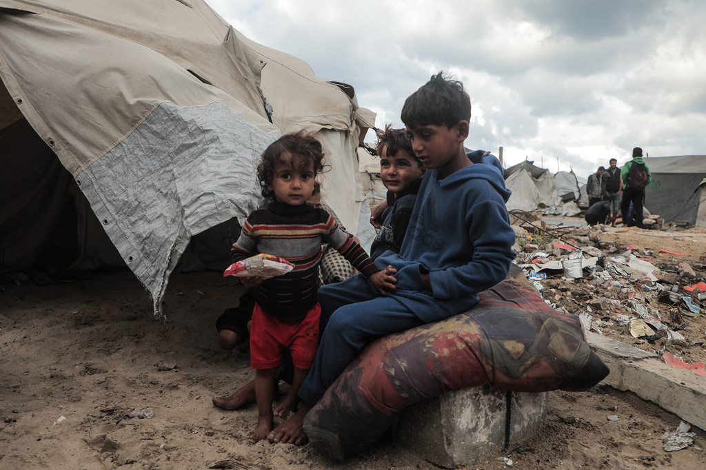 Children sit outside a tent in Gaza.