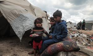 Children sit outside a tent in Gaza.