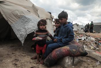 Children sit outside a tent in Gaza.
