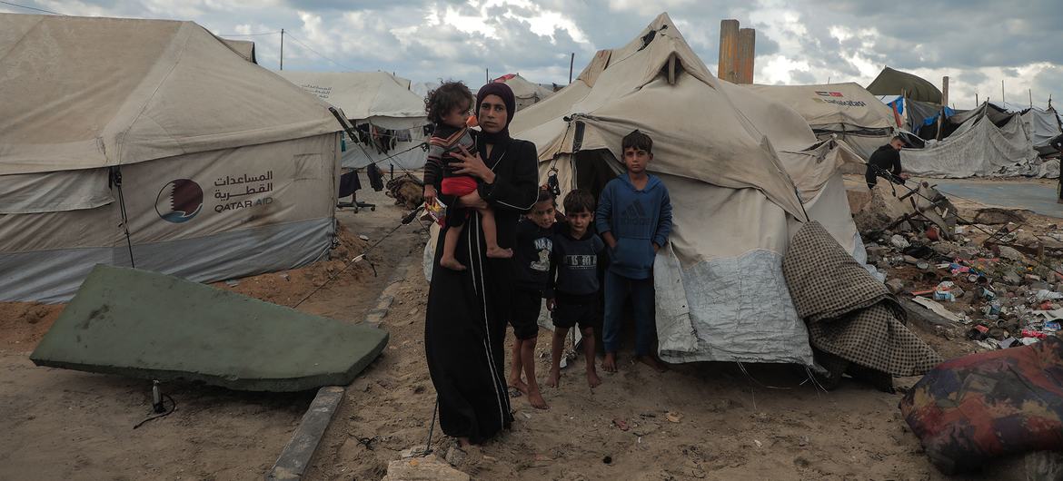 A displaced family stand outside their makeshift tent in Gaza City.