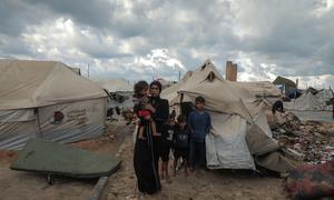 A displaced family stand outside their makeshift tent in Gaza City.
