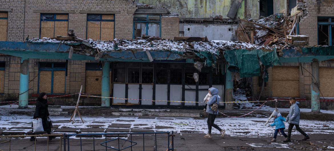 行人从乌克兰库拉霍夫被摧毁的建筑物前经过。