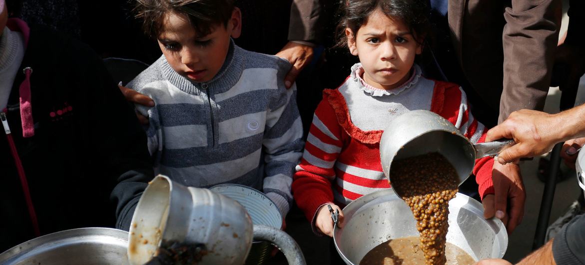 Niños de la Franja de Gaza esperan a que les sirvan comida.