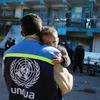 File photo of an UNRWA staff member in Gaza holding a child.