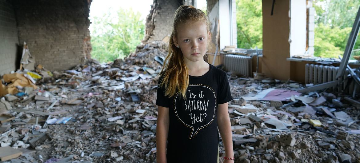 Eight-year-old Anya stands amidst rubble in her damaged school in Buzova, Ukraine.