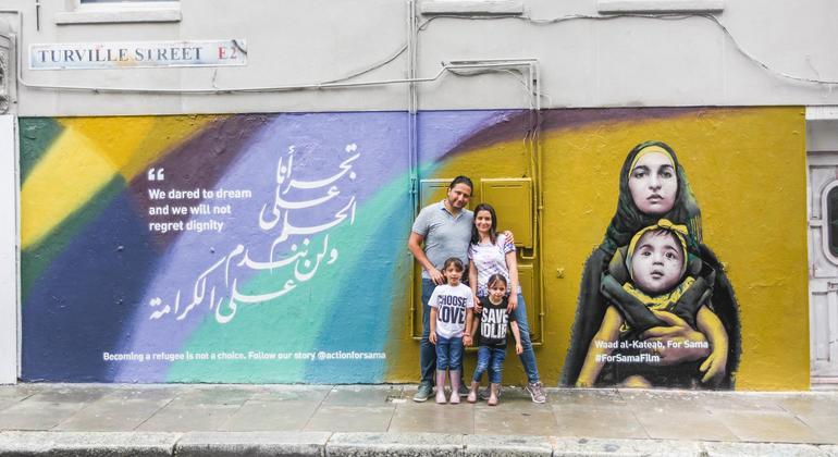 Waad Al-Kateab stands with her family in front of a mural for her film, For Sama.