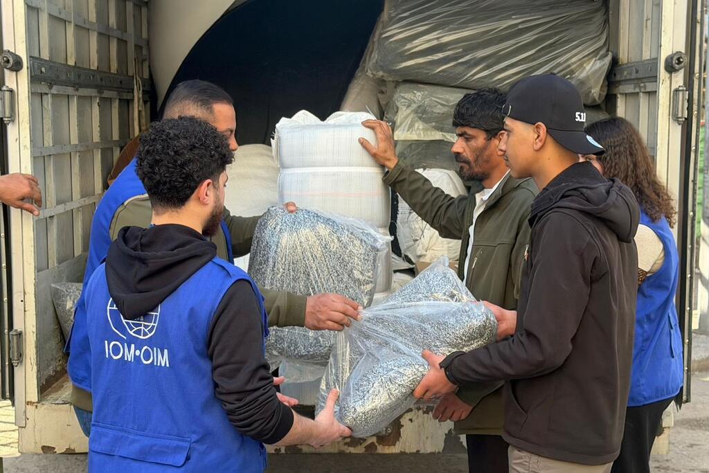 Des travailleurs de l'OIM en gilets bleus déchargent des fournitures d'aide d'un camion pour aider les personnes déplacées au Liban.