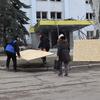 公民在乌克兰斯洛维亚斯克的一个受损建筑前携带大片合板,作为重建工作的一部分.