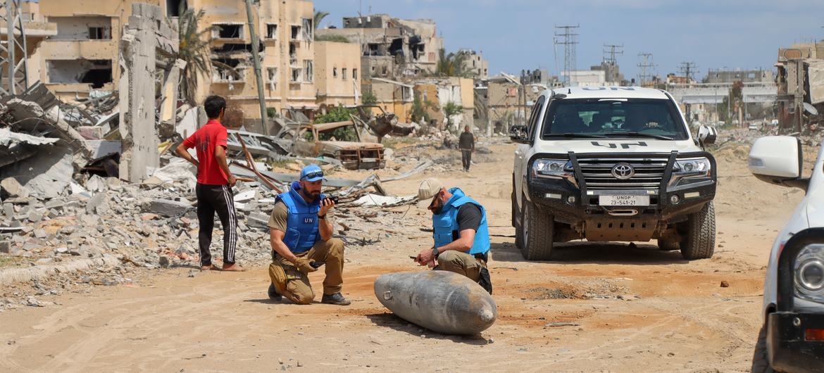 Uma equipe da ONU inspeciona uma bomba não detonada numa estrada principal em Khan Younis, Gaza.