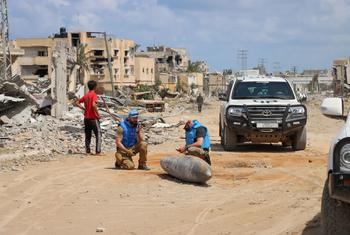 A UN team inspects an unexploded  bomb lying on a main road in Khan Younis, Gaza.