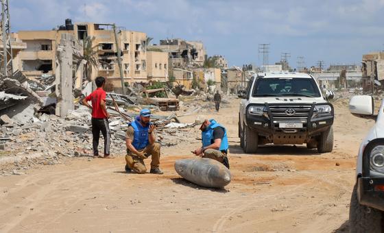 فريق من الأمم المتحدة يتفقد قنبلة غير منفجرة ملقاة على طريق رئيسي في خان يونس بغزة.