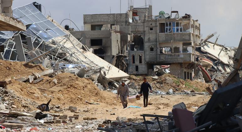 Two people walk thorough the destruction in Khan Younis.