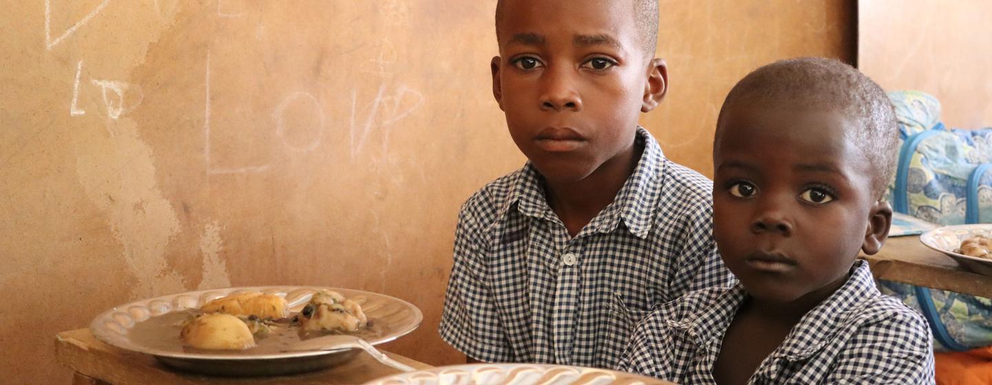 Deux élèves d'une école primaire en Haïti se préparent à manger un repas financé par les Nations Unies.