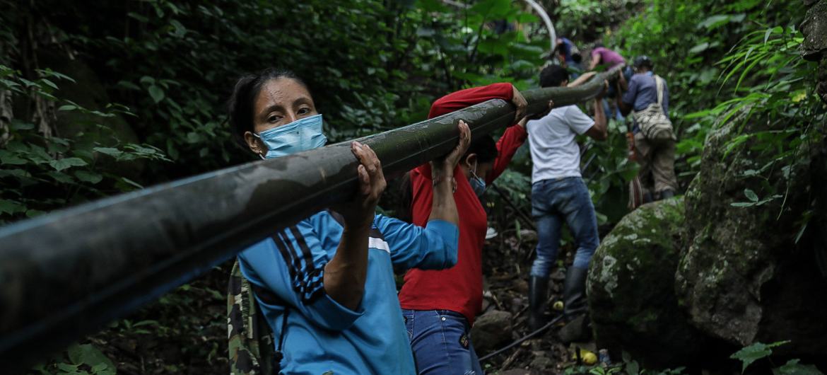 Yarledys Olaya (izquierda), indígena barí que, durante 20 años, fue miembro de la desaparecida guerrilla de las FARC, trabaja junto a otros excombatientes y pobladores locales para construir una tubería de agua.